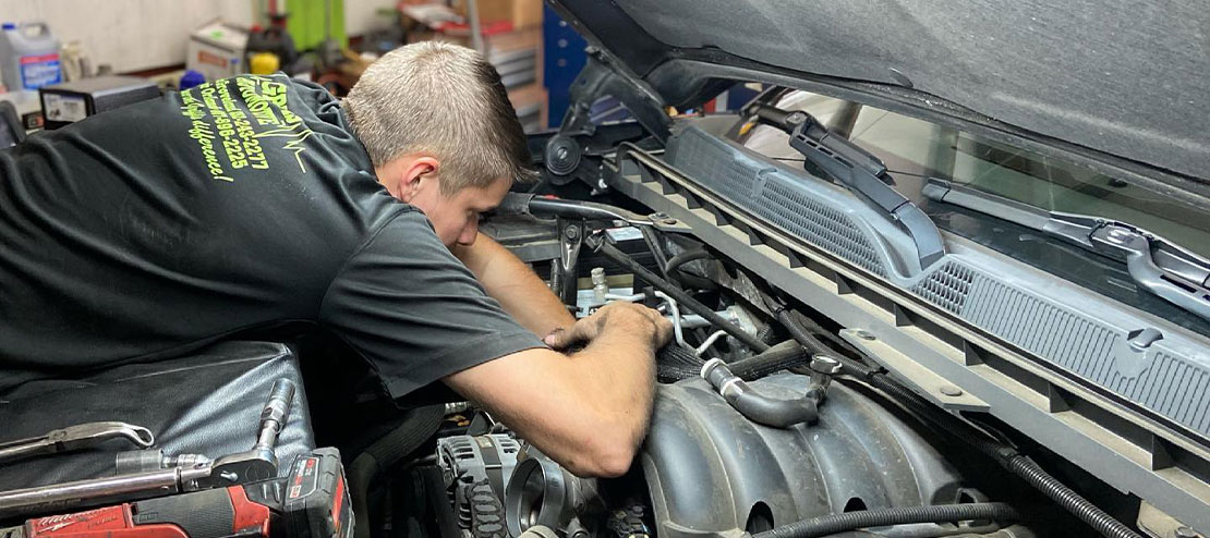 A technician checking the engine of a car under the hood. Concept image of “It’s Time to Prepare Your Car for Summer Road Trips” | Griffis Automotive Clinic In Groveland, FL.