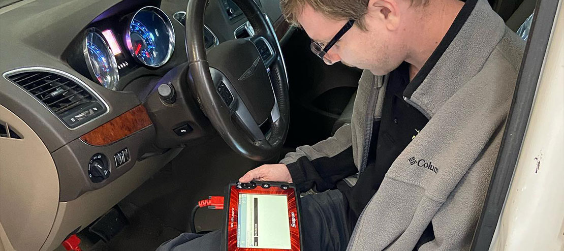 A technician holding a scanner while on the driver seat of a car under checking. Concept image of “Everything You Need to Know About Auto Diagnostics” | Griffis Automotive Clinic in Groveland, FL.
