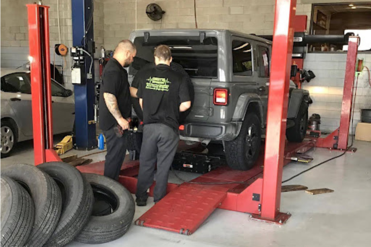 Signs you need a wheel alignment in Groveland, FL. Image of two male mechanics standing behind a gray jeep that is on the wheel alignment machine at Griffis