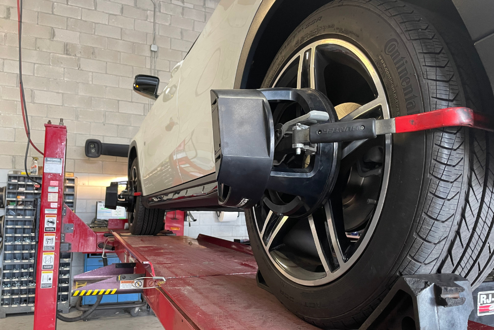 Wheel Alignment services near me in Groveland, FL with Griffis Automotive Clinic. Image of a white car being lifted for inspection of wheel alignment during an auto repair session utilizing state-of-the-art equipment to facilitate precision.