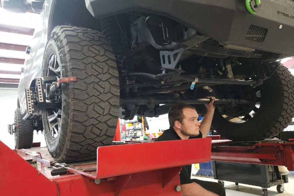 Tire installation and alignment services in Groveland, FL, by Griffis Automotive Clinic. Image of a technician inspecting the underside of a vehicle to ensure proper tire installation and alignment.