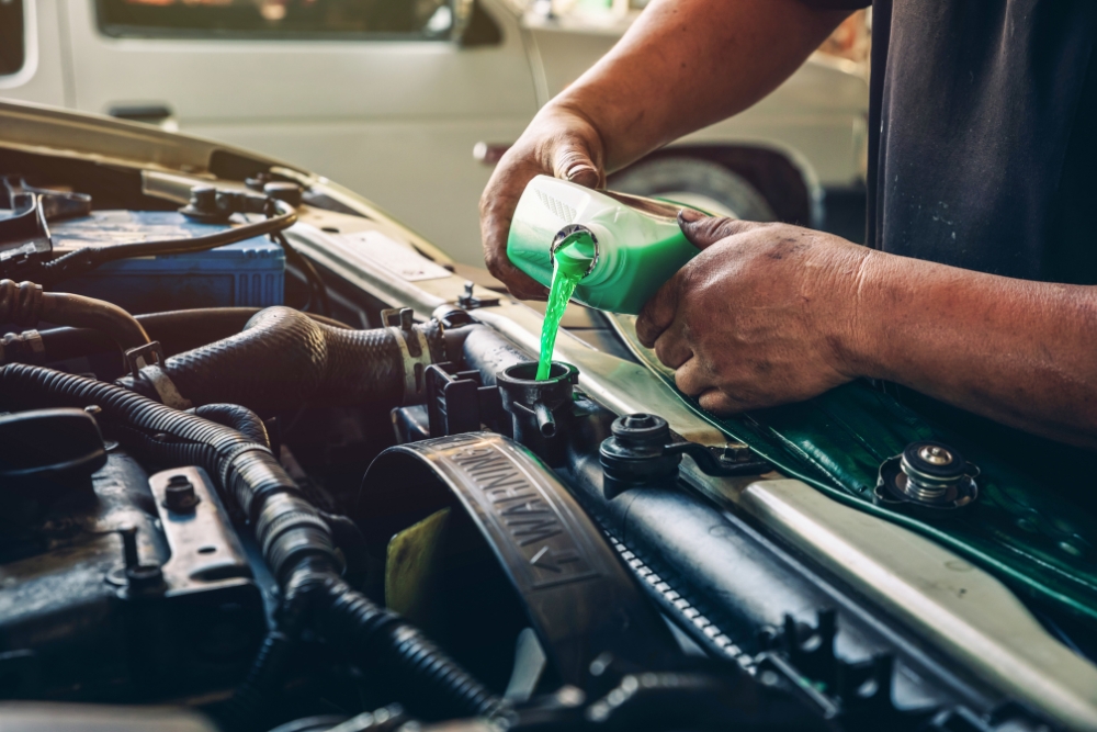 Cooling System Service in Groveland FL At Griffis Automotive Clinic. Close-up of engine coolant being poured into a car radiator during a cooling system service.